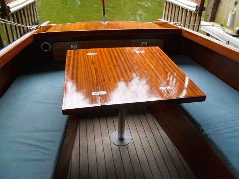 Fold-out table in the cockpit of Frog Prince, surrounded by blue-cushioned seating.