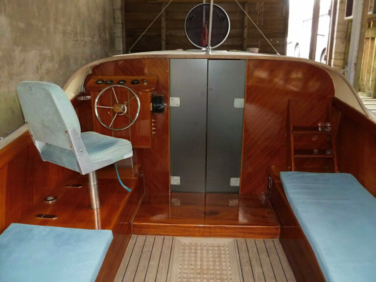 Helm position of Frog Prince with classic wooden dashboard, steering wheel, and forward cabin doors.