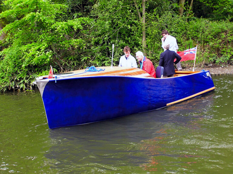 Electric boat Frog Prince cruising on the River Thames with passengers onboard.
