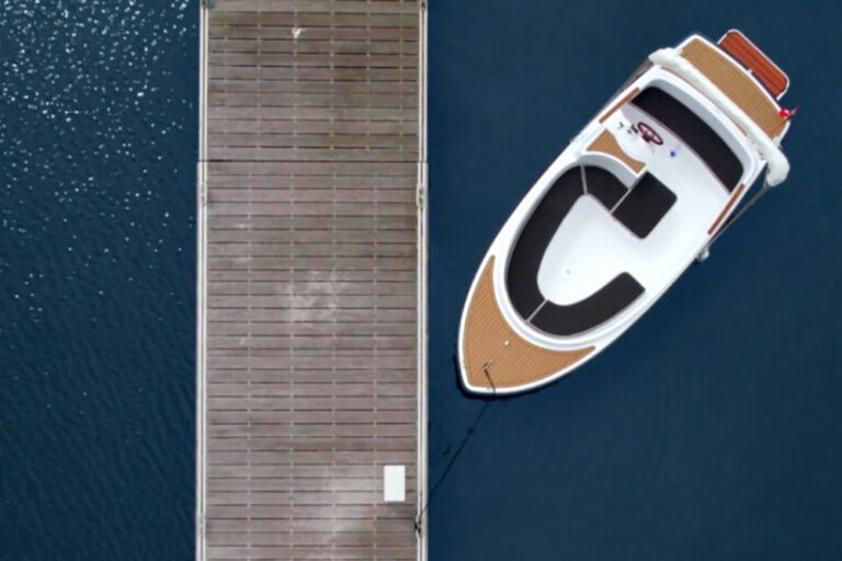 Overhead view of a Ruban Bleu Scoop+ electric launch, moored alongside a wooden dock with faux teak decking.
