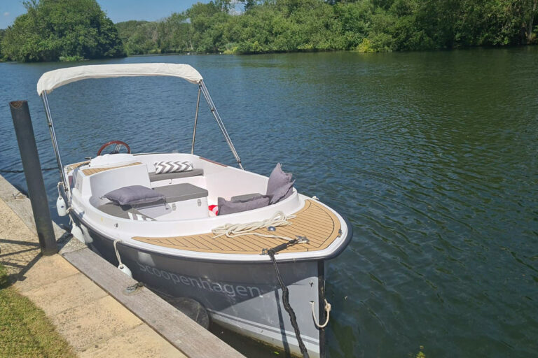 Scoopenhagen electric boat moored on the Thames with bimini and grey cushions on deck.