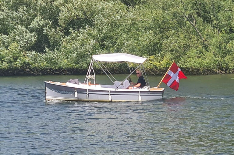 Scoopenhagen Ruban Bleu Scoop+ electric launch, grey hull, canopy raised, cruising the river.